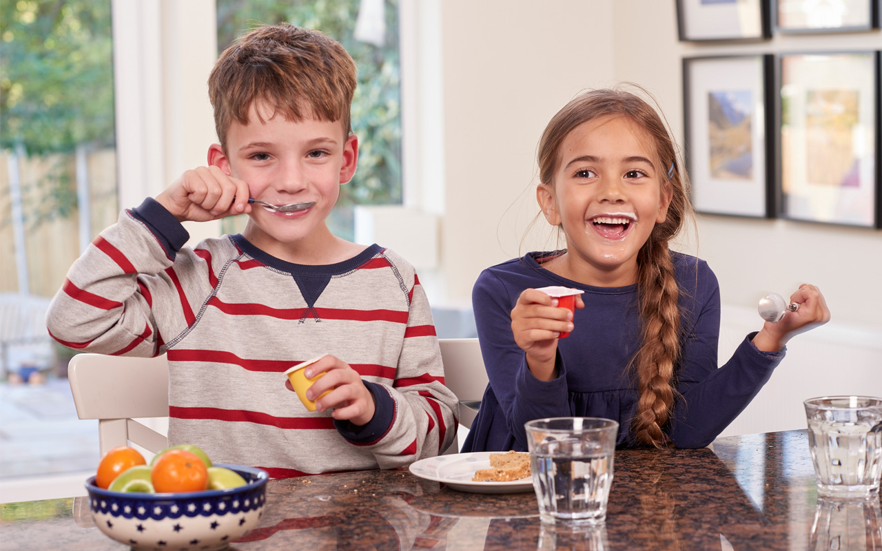 Deux enfants souriants en train de manger des yaourts Danonino en pots 两个微笑的孩子在罐子里吃Danonino酸奶