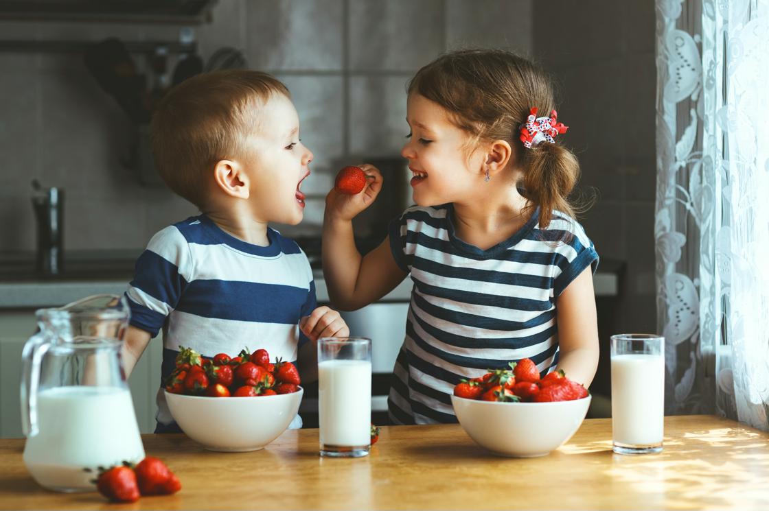 Deux enfants en train de manger des fraises avec un verre de lait 两个孩子正在吃草莓和一杯牛奶
